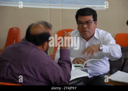 San Cristobal de las Casas, Chiapas, Mexique ; 11 08 2006 ; deux hommes assis sur une chaise dans une salle de classe se parlent avec leurs livres ouverts. Banque D'Images
