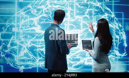 Équipe d'administrateurs utilisant une tablette et un ordinateur portable pour entretenir les réseaux neuronaux d'intelligence artificielle. Membres du personnel INFORMATIQUE travaillant en équipe utilisant un système d'IA aidant au traitement et à la transmission d'informations, caméra B. Banque D'Images