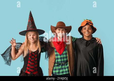 Mignons enfants heureux dans différents costumes habillés pour la fête d'Halloween sur fond bleu Banque D'Images