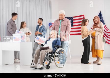 Votant femme senior en fauteuil roulant avec mari et drapeau américain au bureau de vote Banque D'Images