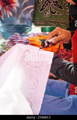 Crafter fabrique des motifs de batik sur tissu à l'aide d'un outil appelé canting. Banque D'Images