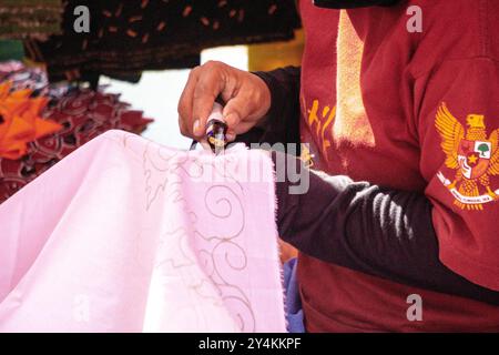 Crafter fabrique des motifs de batik sur tissu à l'aide d'un outil appelé canting. Banque D'Images