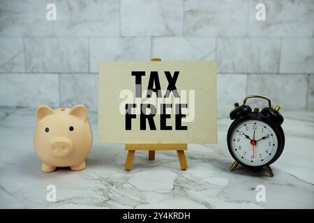 Texte libre d'impôt écrit sur une carte papier avec économie de cochon et réveil sur fond de marbre Banque D'Images