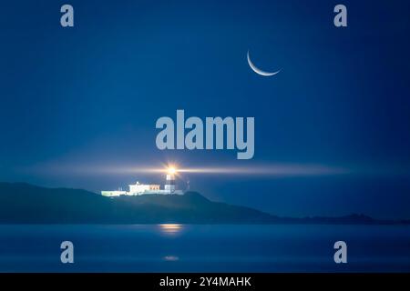 Un croissant de lune illumine un paysage marin nocturne serein, projetant sa douce lueur sur un faisceau de phare. La scène tranquille est parfaite pour la détente et Banque D'Images