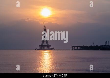 Une silhouette majestueuse du pont Tamsui en construction est baignée dans les teintes dorées du coucher du soleil. La structure inachevée se tient haute contre un V. Banque D'Images