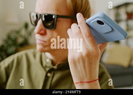 Gros plan moyen du smartphone bleu dans la main d'un homme handicapé Banque D'Images