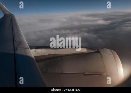 Vue rapprochée d'une turbine d'avion en plein vol contre un ciel nuageux et un effet de lumière du soleil Banque D'Images