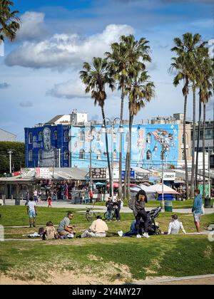 Venice Beach, États-Unis - 31 mars 2024 : personnages accidentels devant Venice Kinesis Street art murale par Rip Cronk contre le ciel bleu avec des nuages Banque D'Images