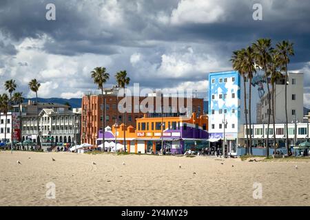 Venice Beach, États-Unis - 31 mars 2024 : promenade en front de mer avec des maisons colorées et des palmiers contre le ciel avec des nuages Banque D'Images