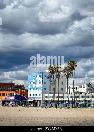 Venice Beach, États-Unis - 31 mars 2024 : promenade en front de mer avec des maisons colorées et des palmiers contre le ciel avec des nuages Banque D'Images