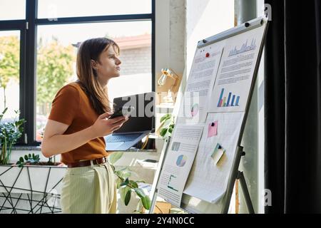 Un jeune individu non binaire focalisé analyse les présentations de données dans un bureau moderne. Banque D'Images