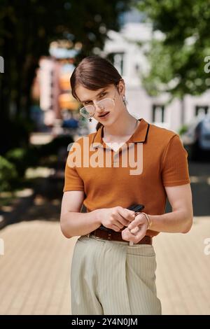 Une personne non binaire dans une tenue chic se tient confiante, se préparant à s'attaquer à des tâches à l'extérieur. Banque D'Images