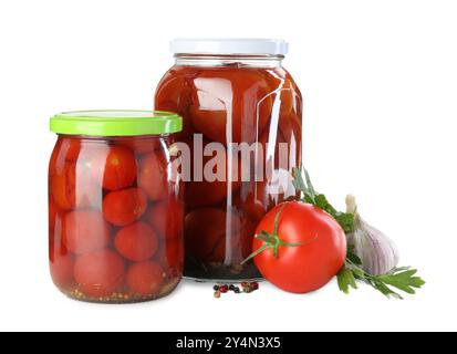 Savoureuses tomates marinées dans des bocaux, légumes frais et épices isolés sur blanc Banque D'Images