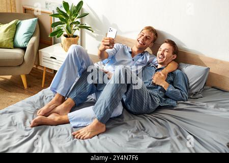 Ce couple joyeux profite d’une matinée cosy ensemble, souriant et partageant un moment de lumière dans leur pyjama. Banque D'Images