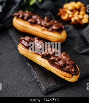 Deux eclairs avec du chocolat noir sur tableau noir Banque D'Images