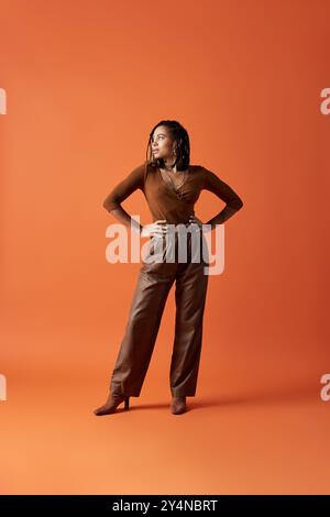 Une jeune femme afro-américaine à la mode présente son style avec des cheveux tressés dans un studio dynamique. Banque D'Images