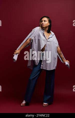 Une jeune femme afro-américaine à la mode met en valeur son style vibrant dans un cadre de studio audacieux. Banque D'Images