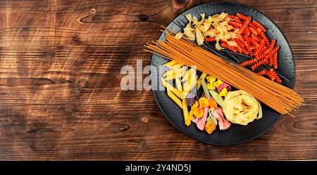 Divers types de pâtes non cuites, nouilles et spaghettis sur une vieille table rustique en bois. Espace pour le texte. Banque D'Images