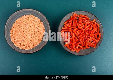 Pâtes végétaliennes non cuites ou macaroni, fusilli de lentilles rouges sur la table de la cuisine. Banque D'Images