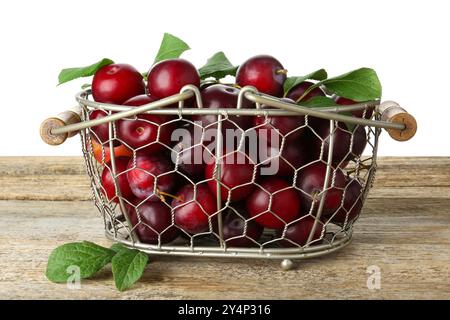 Beaucoup de prunes mûres dans le panier sur la table en bois sur fond blanc Banque D'Images