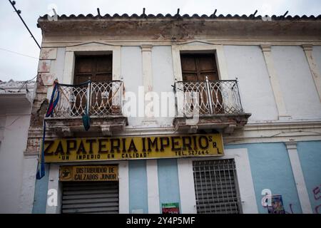 Bâtiment délabré dans une ville andine. La façade du bâtiment est un mélange de peinture écaillée et de briques apparentes, montrant des signes de négligence et de décomposition. Banque D'Images