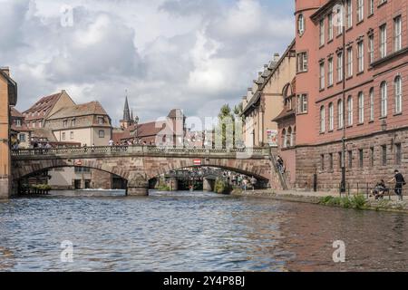 STRASBOURG, 2024 sept 04 : paysage urbain avec des touristes marchant sur le pont piétonnier saint Martin sur la rive de l'Ill près de petite France borrough, tourné en bri Banque D'Images