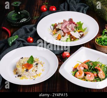 différentes salades dans des assiettes blanches sur une table en bois Banque D'Images