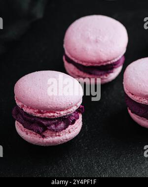 Macarons roses garnis de chocolat sur pierre noire Banque D'Images