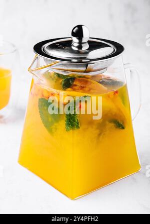 thé à la menthe et à l'orange. boisson chaude aromatique dans un pot en verre. Banque D'Images