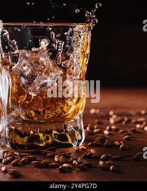 Splash de whisky d'un cube de glace dans le verre Banque D'Images