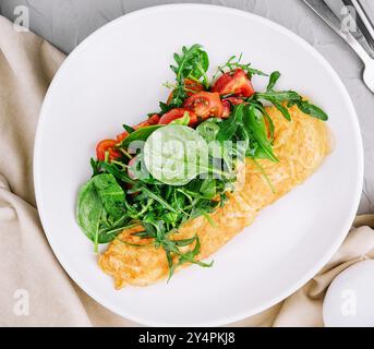 Omelette avec roquette, tomates et basilic dans une assiette Banque D'Images