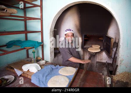 Chefchaouen, Maroc, 3 juillet 2007, Un boulanger prépare habilement du pain dans un four commun, mettant en valeur la tradition culinaire locale de la ville de Chefch Banque D'Images