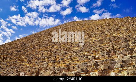 Une vue ascendante depuis la base de la Grande Pyramide de Khufu avec ses énormes blocs de calcaire tura contre un ciel bleu brillant sur le plateau de Gizeh Banque D'Images