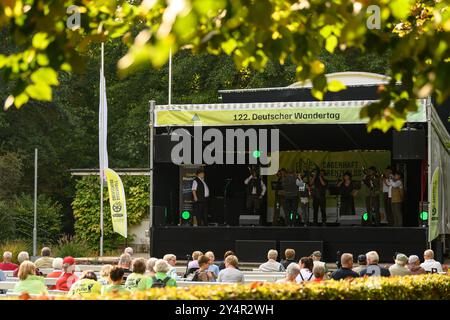 Heilbad Heiligenstadt, Allemagne. 19 septembre 2024. Les amateurs de randonnée s'assoient devant une scène lors de la 122ème Journée allemande de randonnée 2024. La Journée allemande de la randonnée est un rassemblement annuel de passionnés de randonnée et a lieu du 19 au 22 septembre 2024. Crédit : Swen Pförtner/dpa/Alamy Live News Banque D'Images