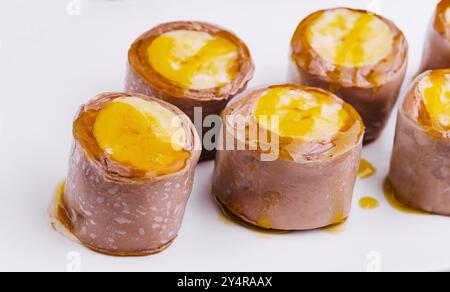 Rouleaux de crêpes à la banane au chocolat sur assiette blanche Banque D'Images