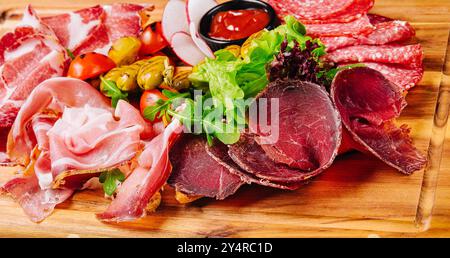 Variété de viandes, saucisses, salami, jambon, olives, disposé sur une planche de bois Banque D'Images