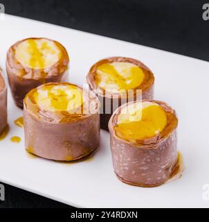 Rouleaux de crêpes à la banane au chocolat sur assiette blanche Banque D'Images