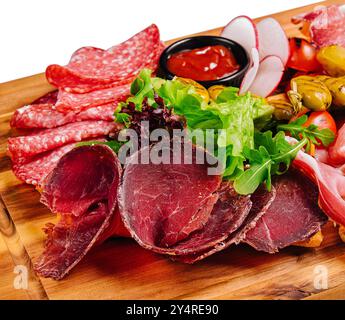 Variété de viandes, saucisses, salami, jambon, olives, disposé sur une planche de bois Banque D'Images