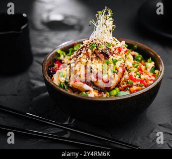 Salade avec anguille et couscous sur bol noir Banque D'Images