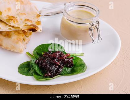 pâté de poulet avec confiture d'oignons et pain pita servi dans une assiette blanche Banque D'Images