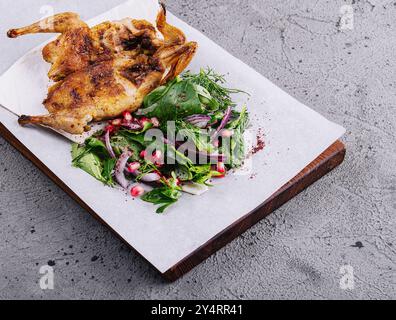 Caille grillée rôtie sur planche à découper en bois avec garniture de salade verte Banque D'Images