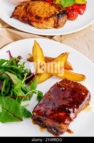 côtes de porc avec pommes de terre et steak de porc avec légumes grillés Banque D'Images