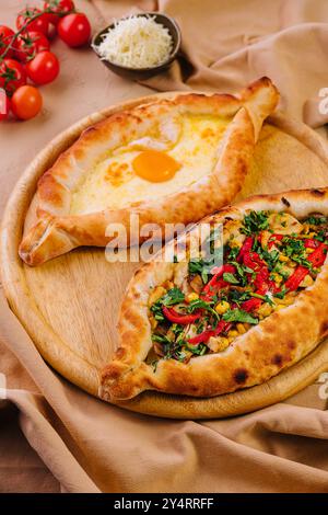 Cuisine géorgienne - adjarien khachapuri avec oeuf et megrelian avec fromage et légumes verts Banque D'Images