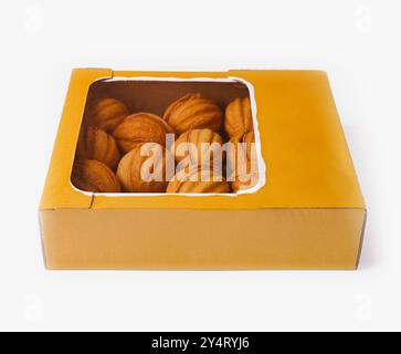 Boîte jaune remplie de biscuits fraîchement cuits en forme de noix isolés sur fond blanc Banque D'Images