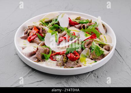 Carpaccio de boeuf en tranches orné de copeaux de parmesan, de roquette et de poivrons rouges Banque D'Images