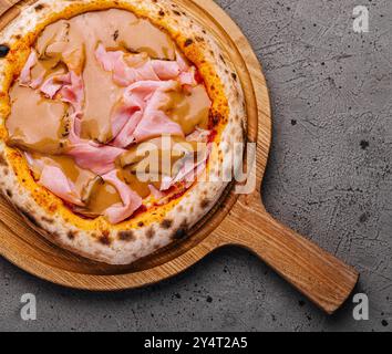 Vue de dessus d'une délicieuse pizza au jambon servie sur une planche de bois rustique, prête à être dégustée Banque D'Images