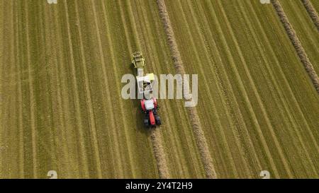 Un tracteur avec une presse à balles de paille dans un champ Banque D'Images