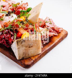 Élégant panneau de charcuterie avec une variété de fromages, de charcuteries et de garnitures sur une surface en bois Banque D'Images