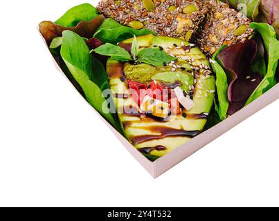 Repas végétalien nutritif avec avocat, légumes verts mélangés et barres de graines dans une boîte à emporter Banque D'Images