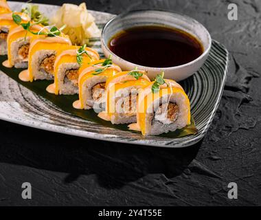 Petits pains de sushi gourmands avec garniture à la mangue, servis avec sauce soja et gingembre sur une assiette chic Banque D'Images